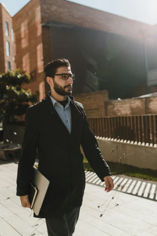 a young man walking down the sidewalk carrying his suit