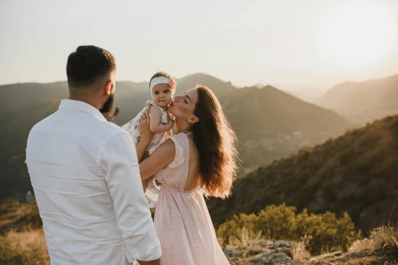 a man and a woman are holding a baby above some mountains