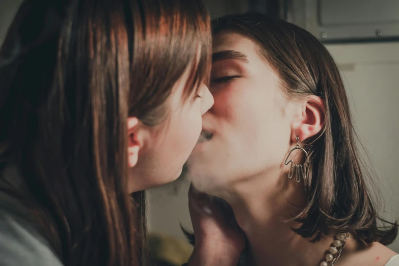 two women with earrings and pearls kissing each other