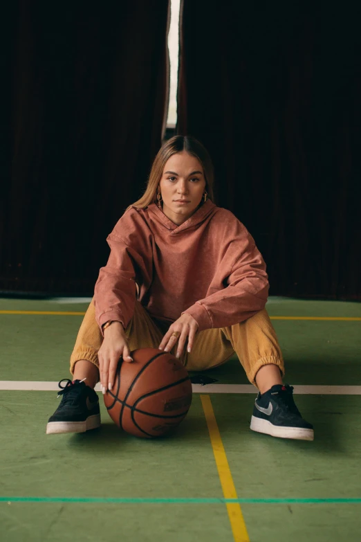 a woman in a brown shirt is holding a basketball