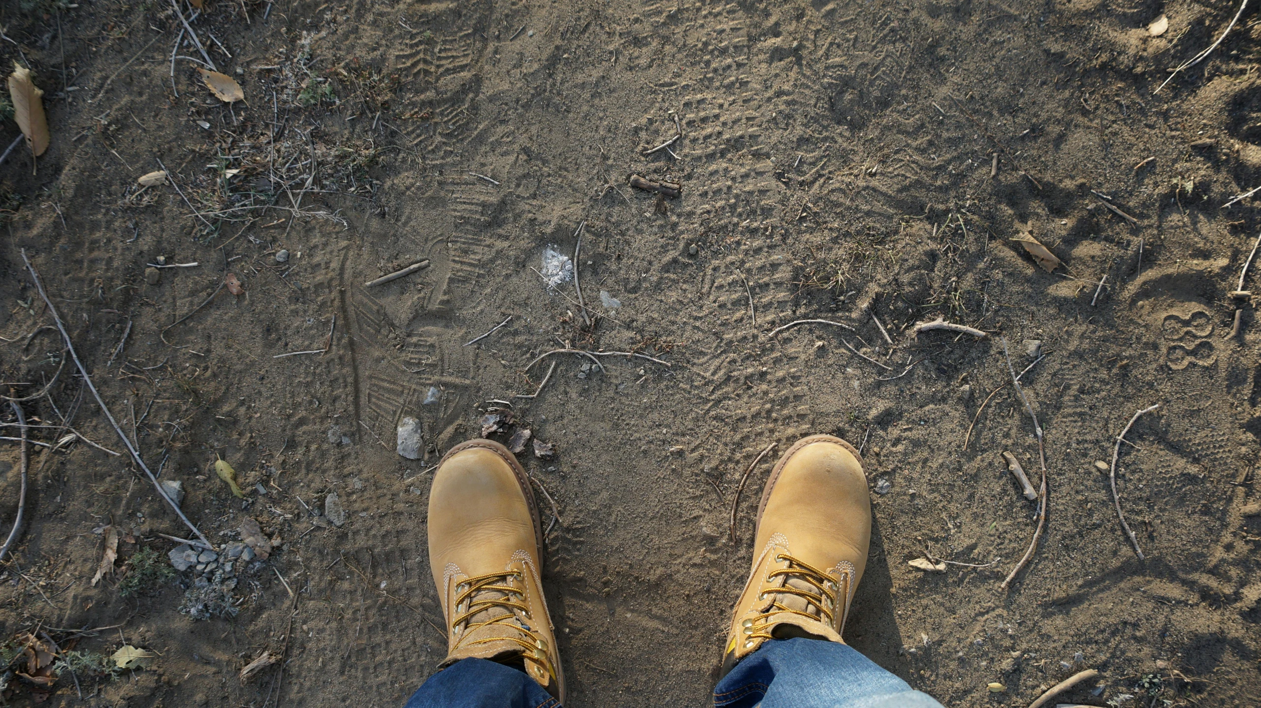 a man wearing tan shoes in the middle of a dirt area