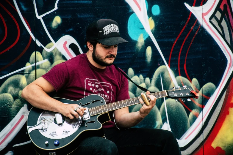 a man is playing his guitar in front of a wall