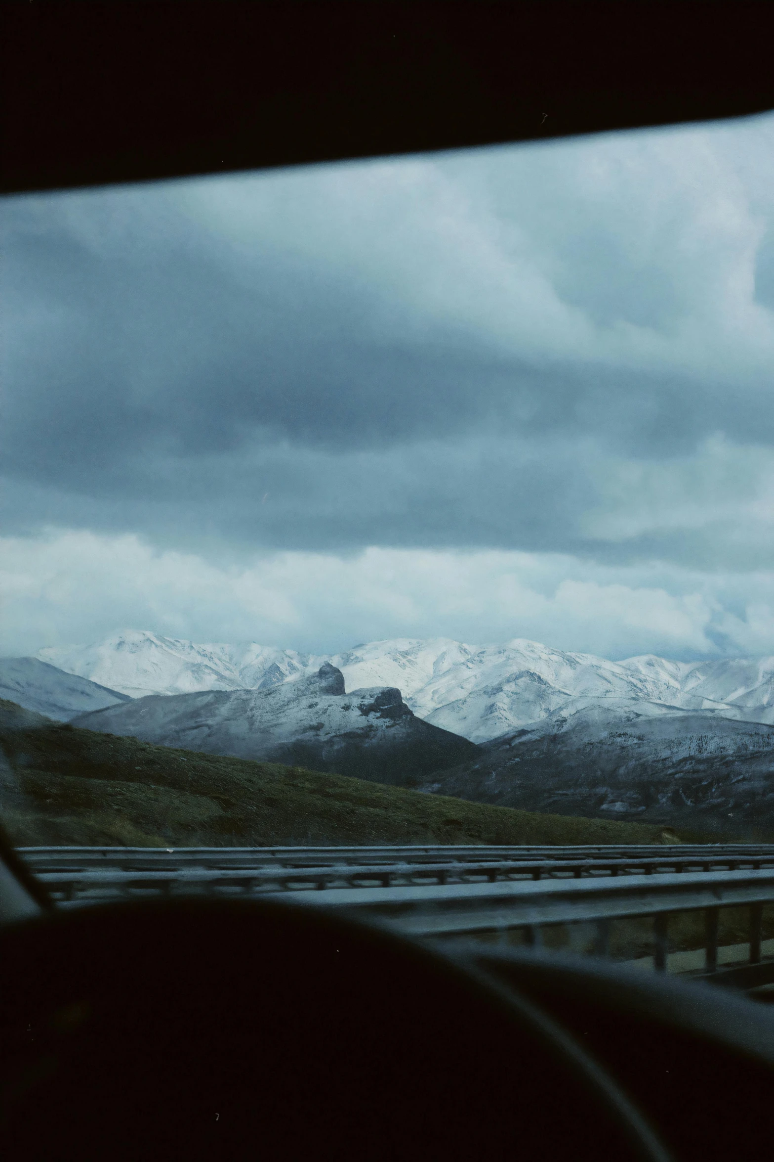 a road with mountains, with clouds and a mountain in the distance