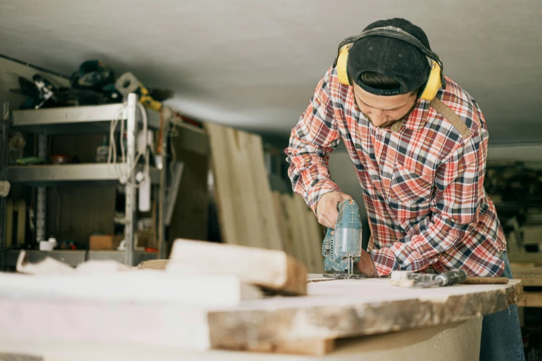 a man using a machine to cut a piece of wood