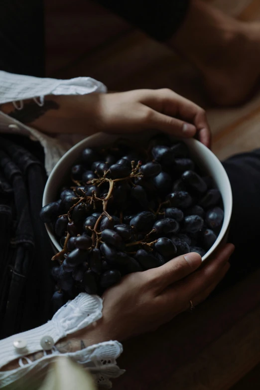 a person's hands holding a bowl of black gs