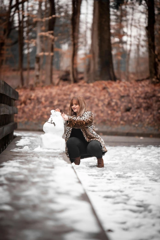 the woman has some snow and is building a snow man