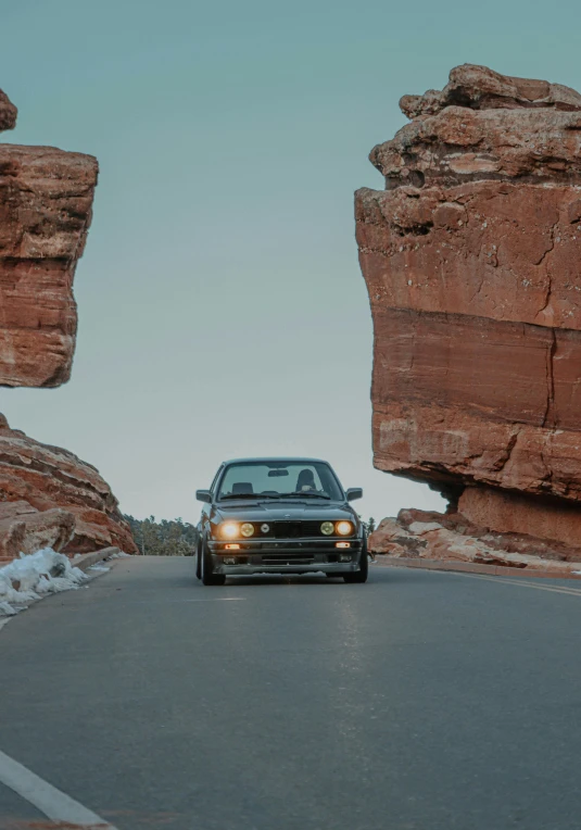 car going down street between two large red rocks