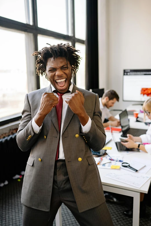 a man wearing a suit is laughing while holding his hands together