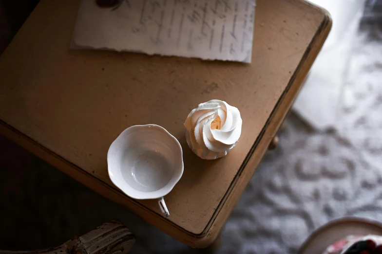 an old table with some coffee cups and flower