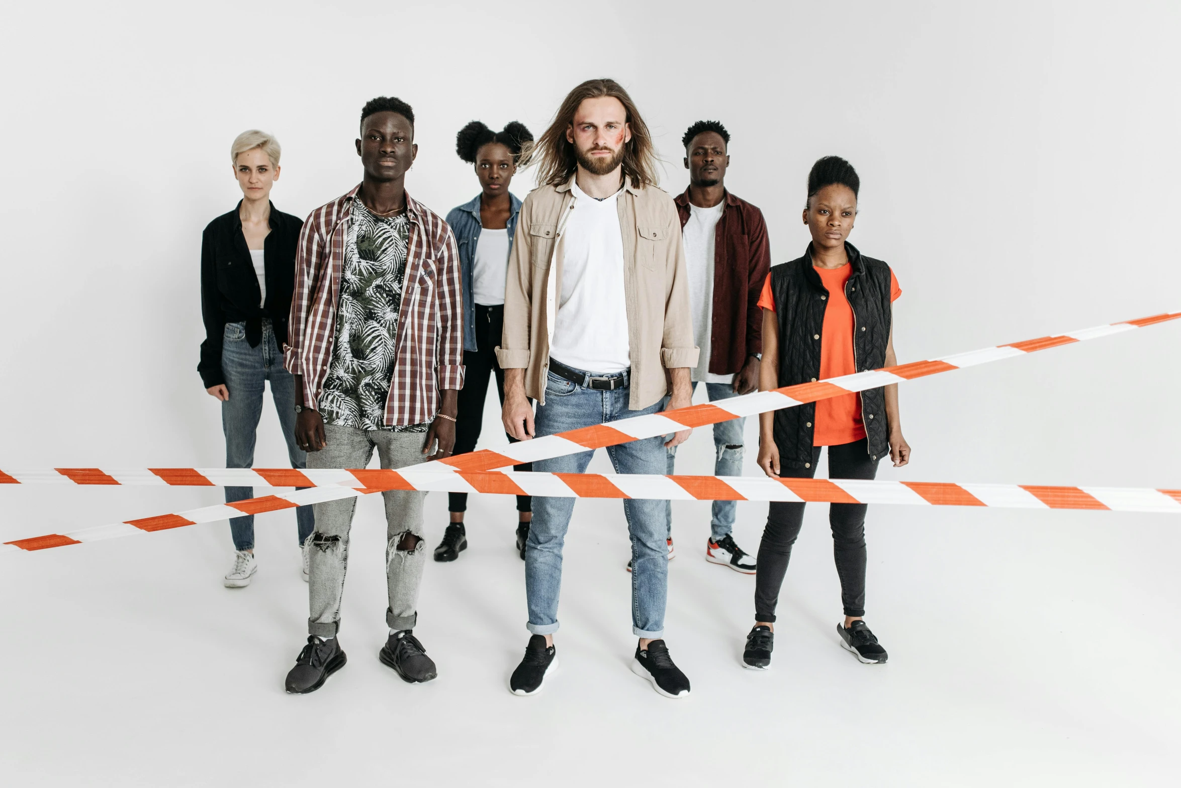 the group of young adults stands near the ribbon that is taped up