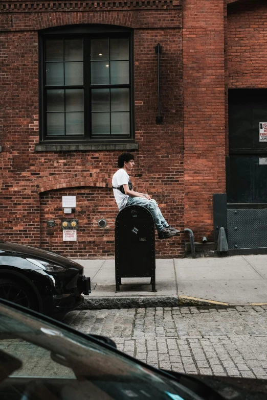 a man sits on top of a small trash can