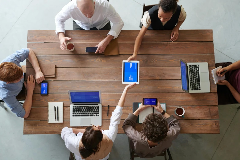 three people at a long table with laptops and coffee