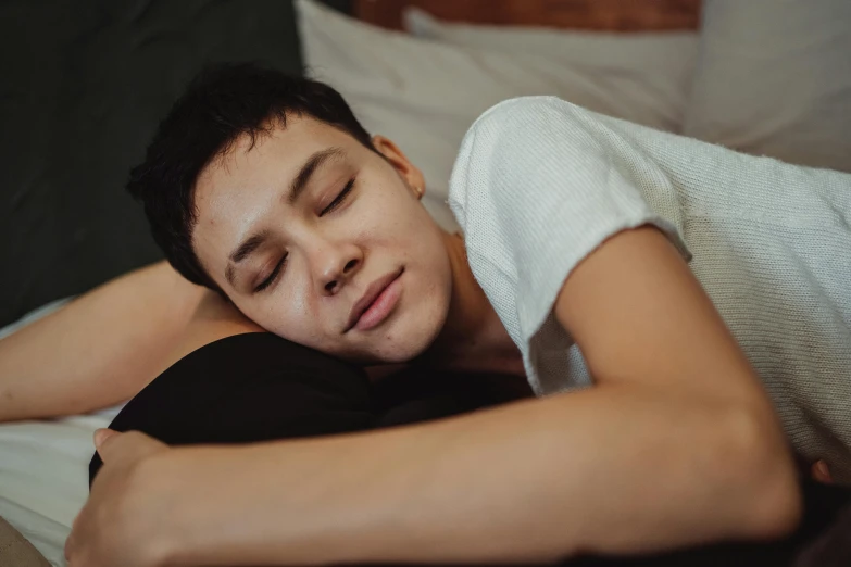 a young man asleep on his side in bed