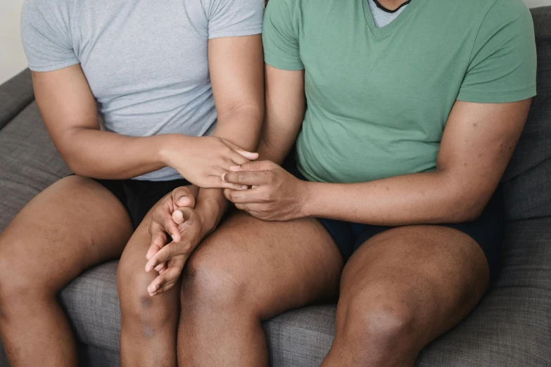 two men sitting on top of a grey couch