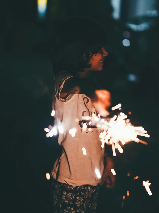 a girl looking at the light from her firework