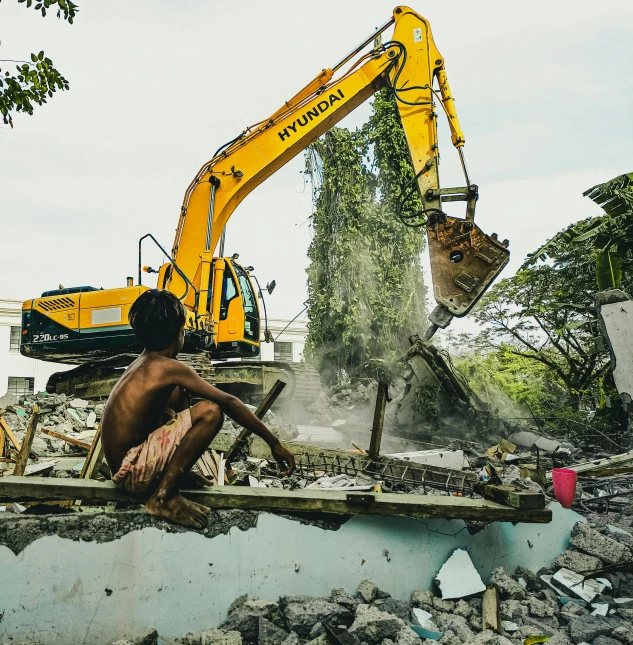 a construction worker excavating the rubble with a machine