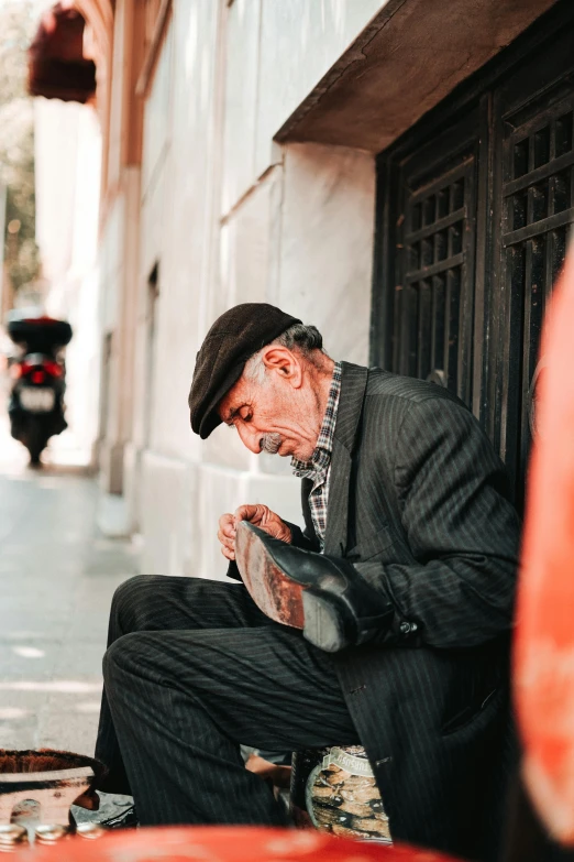 a man sits on the side of a street with his instrument