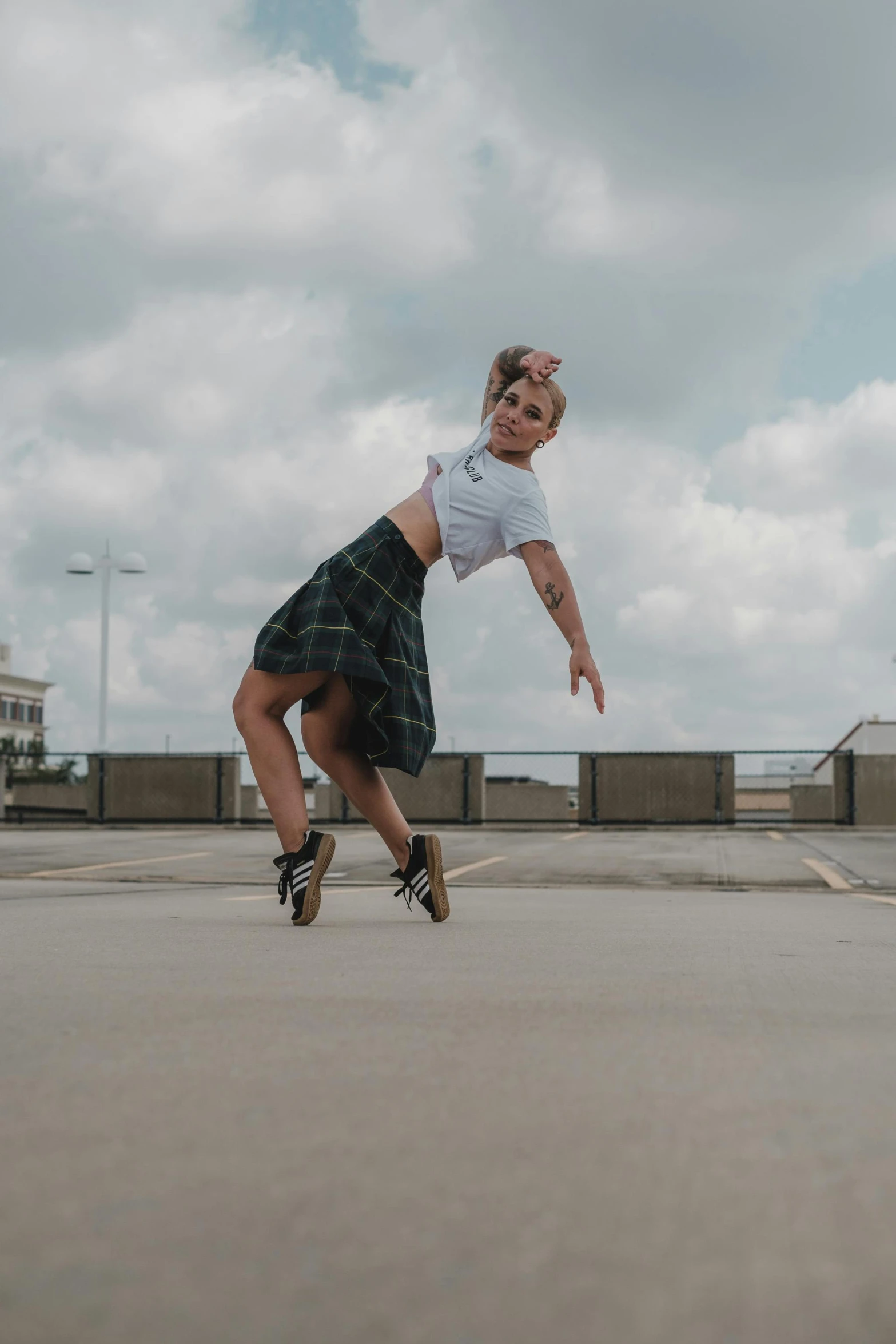 a woman in white shirt and plaid skirt skateboarding