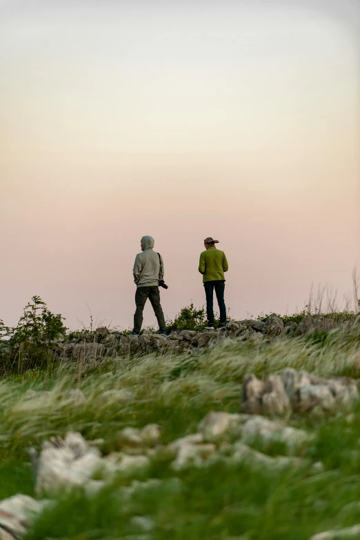 two men with backpacks standing on rocky cliff