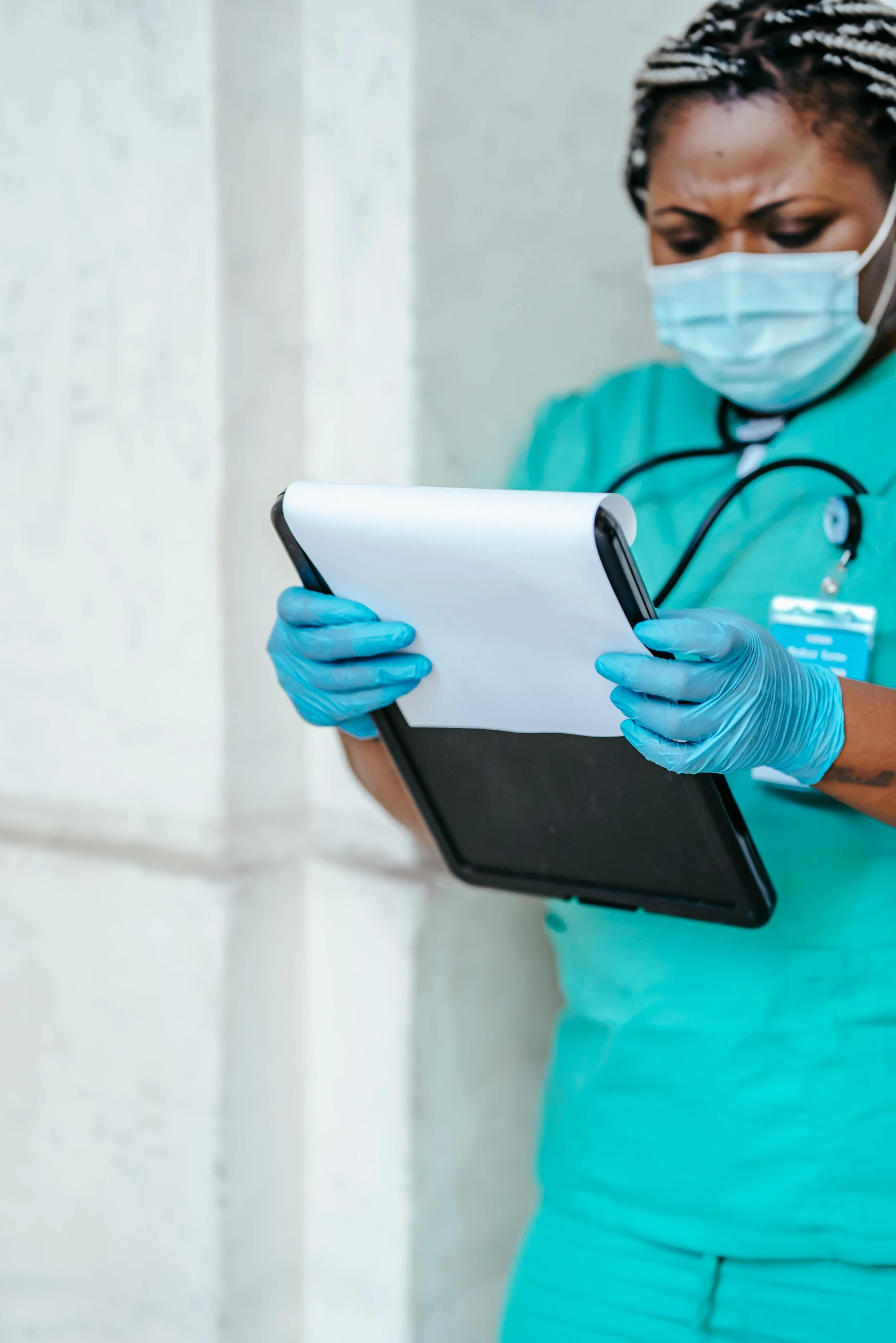 a woman in green scrubs is using a tablet