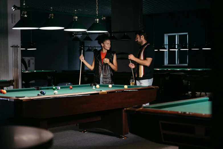 two people at pool tables hold their sticks for the game