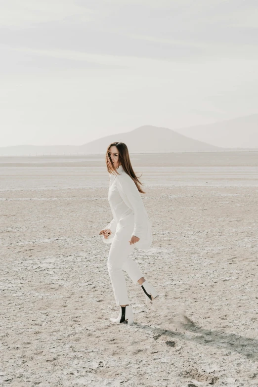 a woman in white is walking across a desert