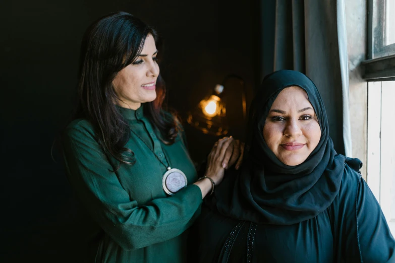 two women standing in front of a window in the dark