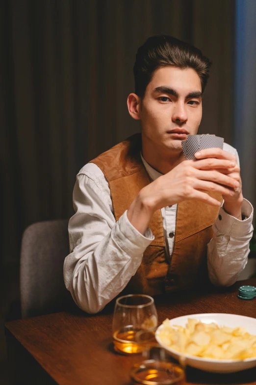 a young man sits at a table in front of a plate with chips and drinks