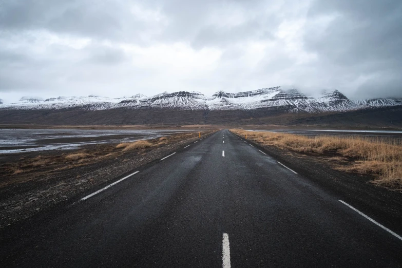 an empty street leading to a mountain with snow