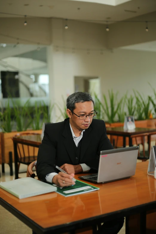 a man with a pen and laptop at a table