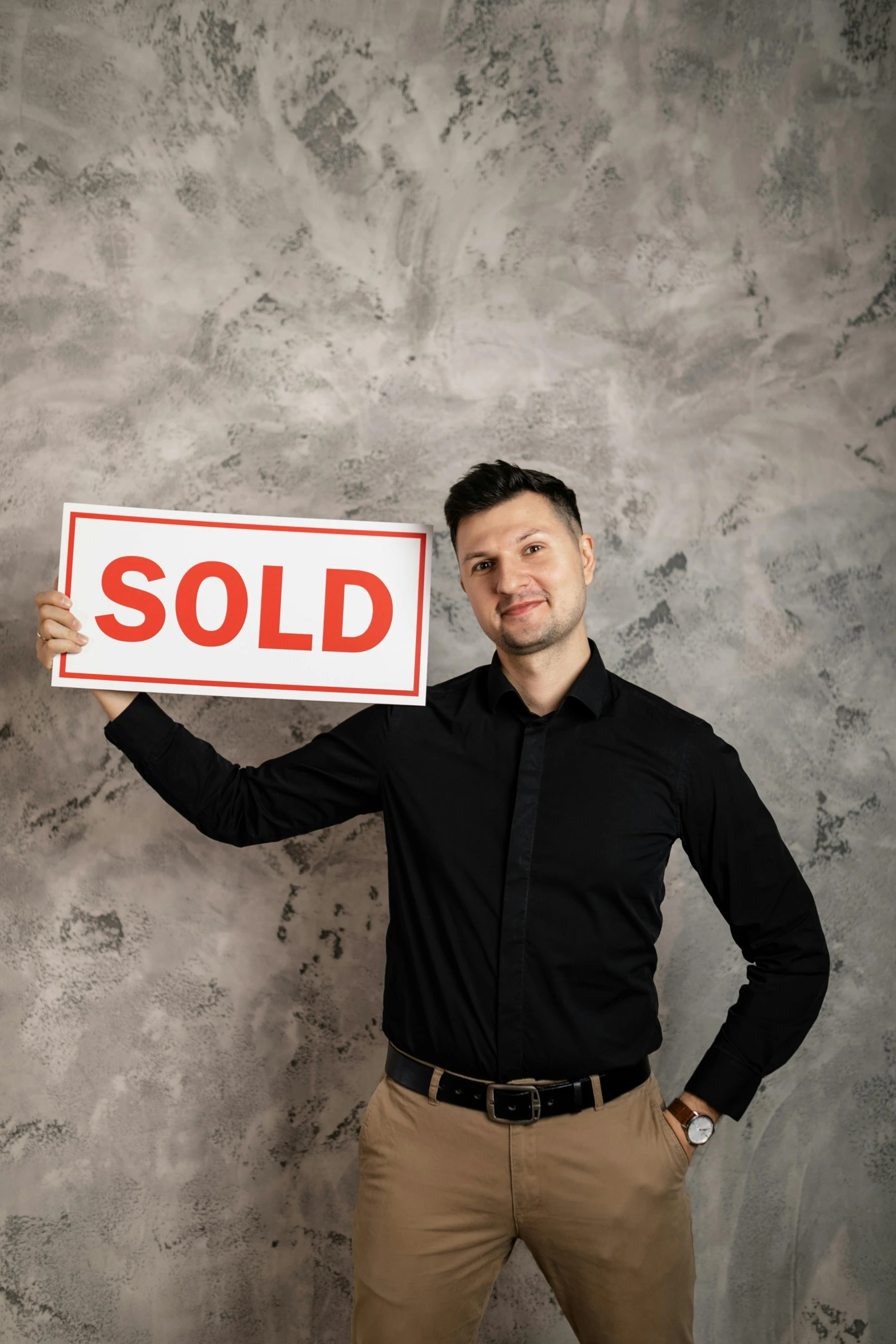 a man holds up an sold sign to show the word sold