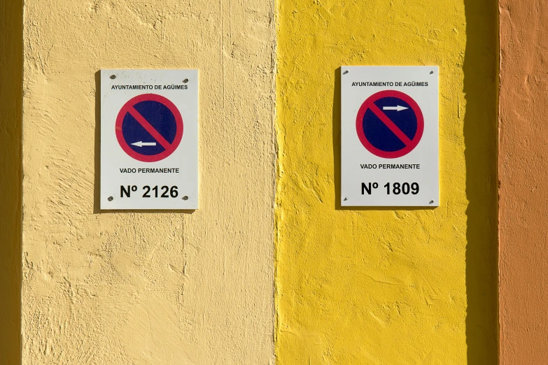 two signs attached to a wall, on a yellow and orange background