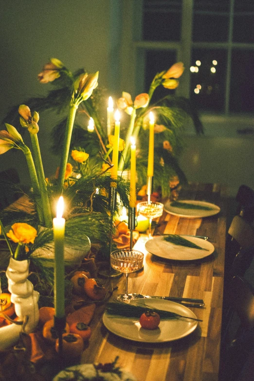 a dinner table set with a flower centerpiece and candles in the center