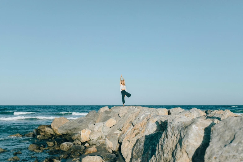 a woman standing on rocks near the ocean