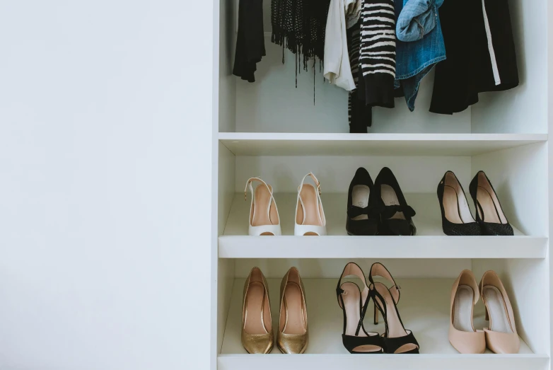 an open white closet that is filled with shoes and scarves