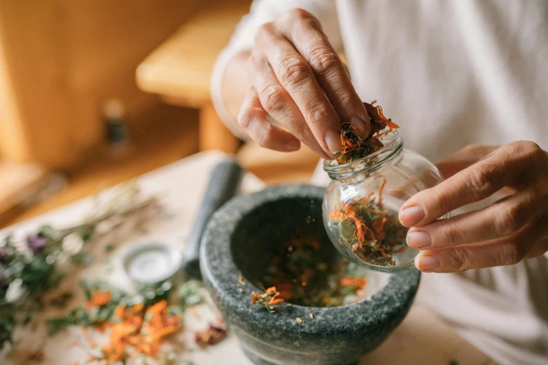 a person is preparing dried flowers into an individual jar