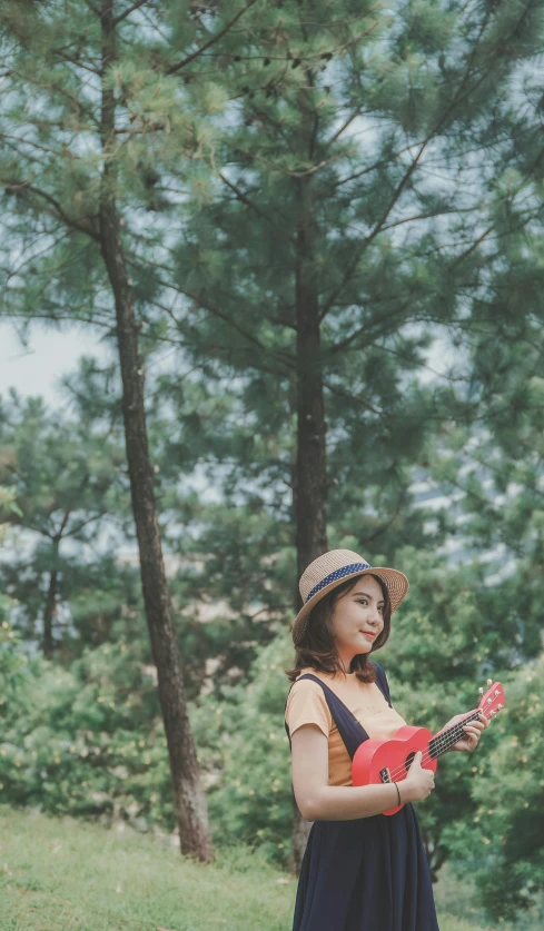 woman with straw hat holding guitar outdoors