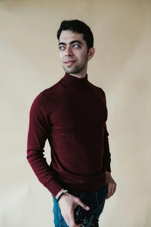 a man in a red sweater and jeans holding a camera