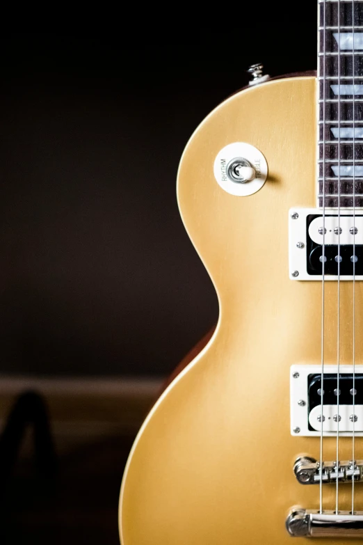 a yellow guitar is sitting on a dark surface