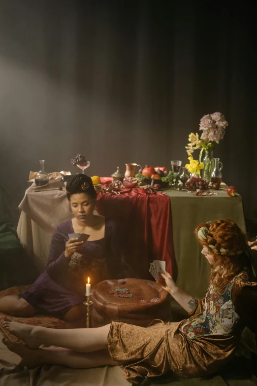 two women sitting at a table while the lady uses her phone