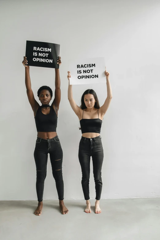 two young women holding signs with words across the signs