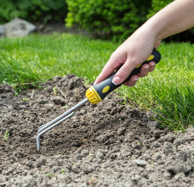 someone holding a garden tool and digging dirt