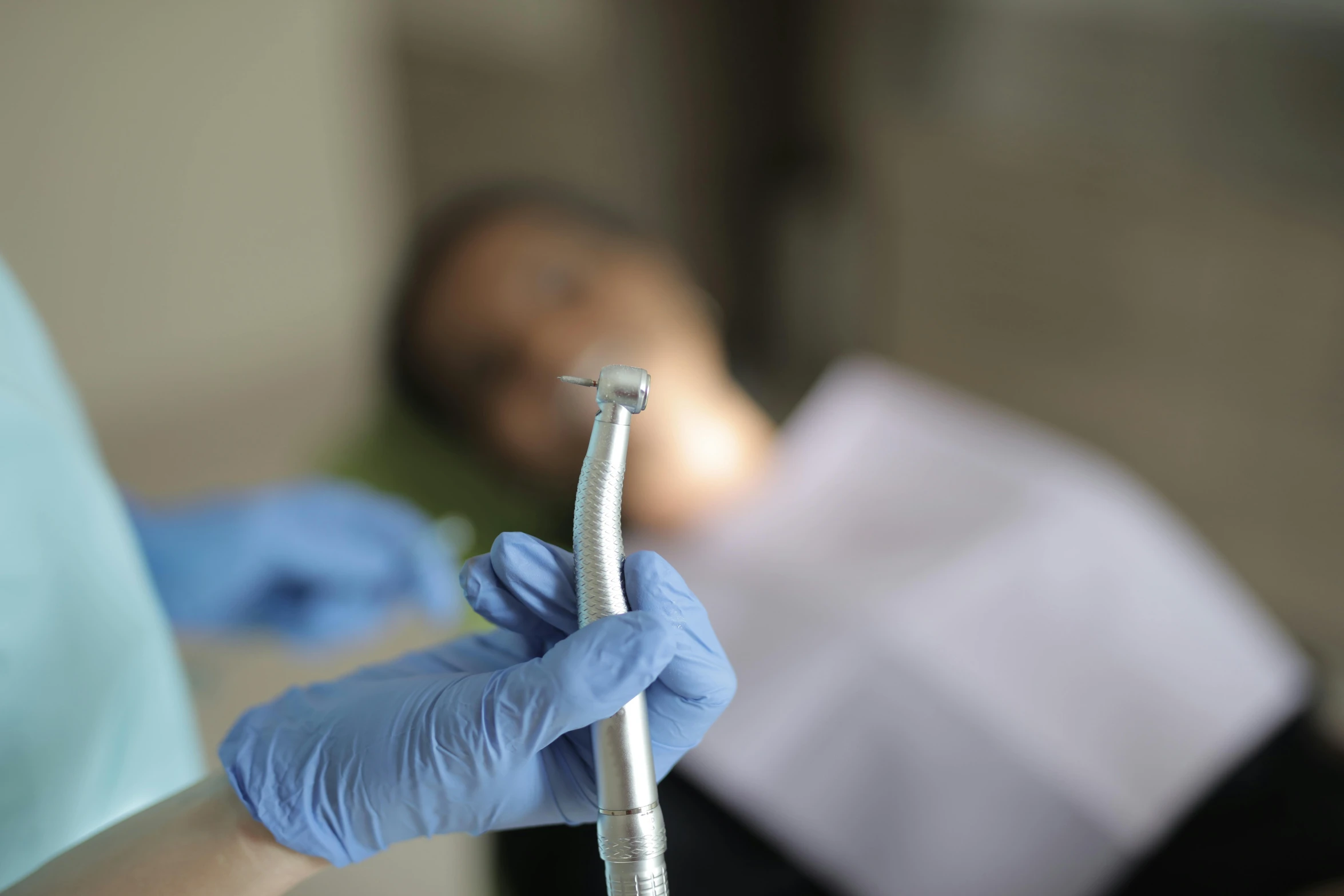 a woman in blue gloves holds a tooth brush