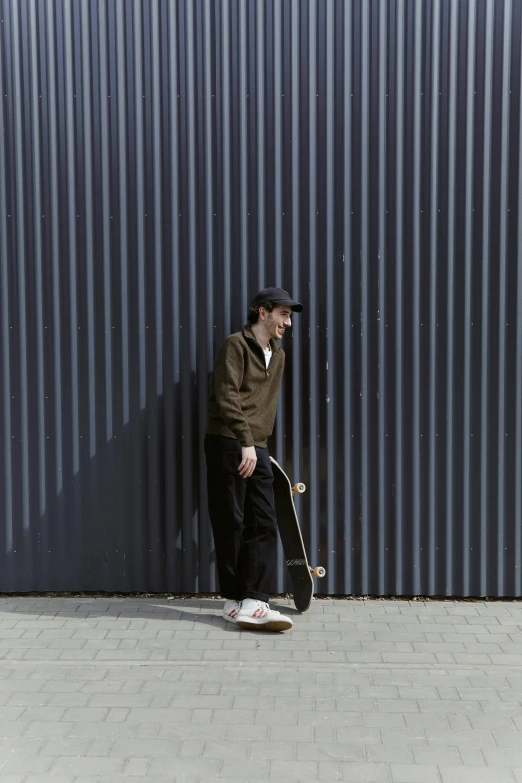 a man is holding a skateboard next to a wall