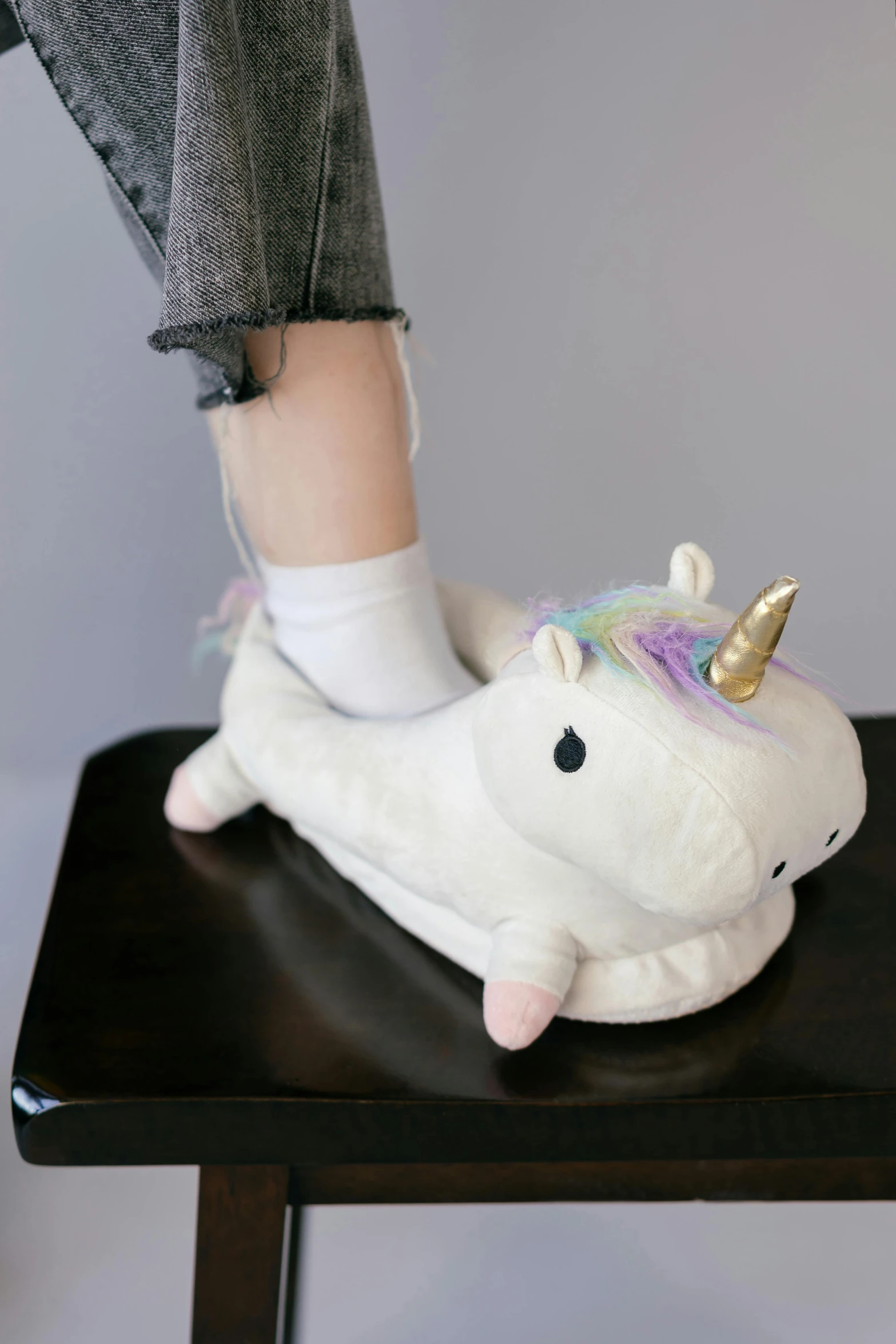 a person's feet on top of a stuffed toy unicorn