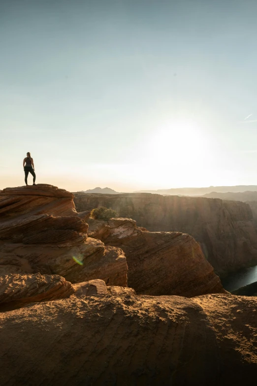 a lone person stands on top of a high cliff above the river