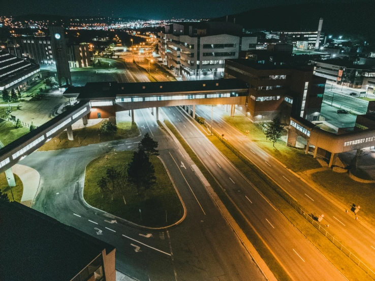 an aerial view of a highway at night with several buildings and traffic