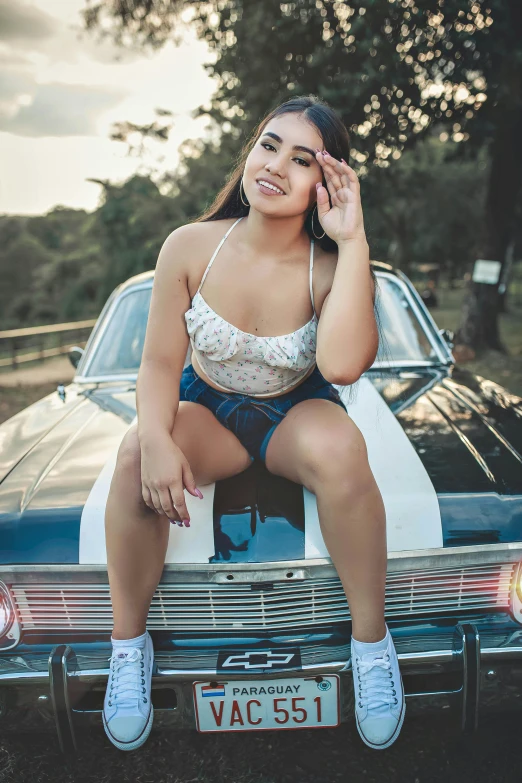 a girl in her underwear sitting on the hood of a car