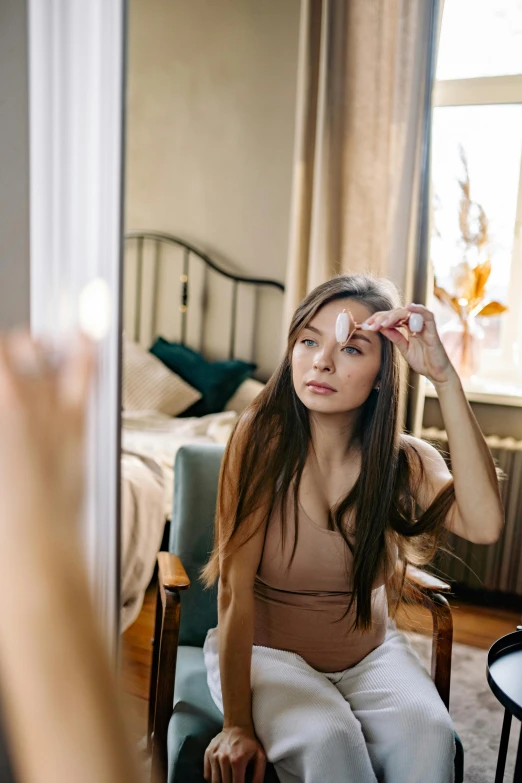 a woman sitting in a chair looking at her reflection