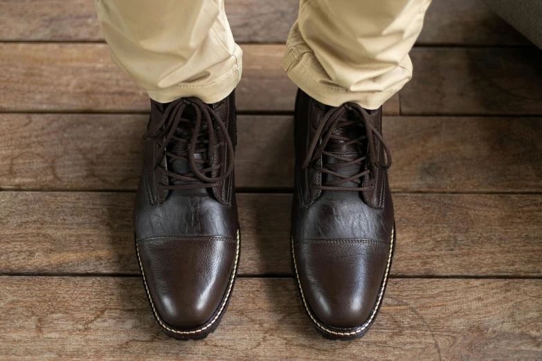 a man in brown shoes standing on a wooden floor